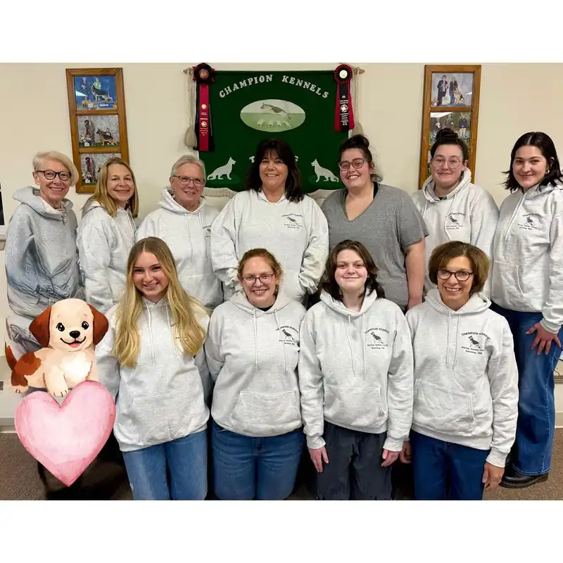 The Champion Kennels staff together in matching hoodies in front of the kennel banner